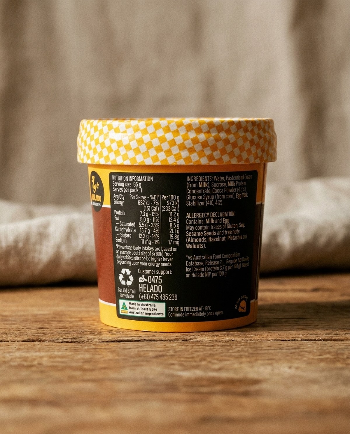 A Helado Chocolate Fix cup standing on a wooden bench, its back panel turned to the camera